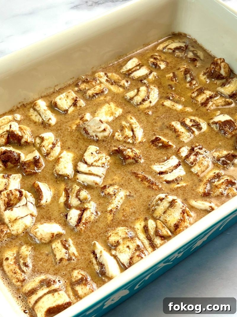 Cinnamon Roll French Toast Casserole Recipe for Brunch Bliss 7 Egg mixture poured over cinnamon roll pieces.
