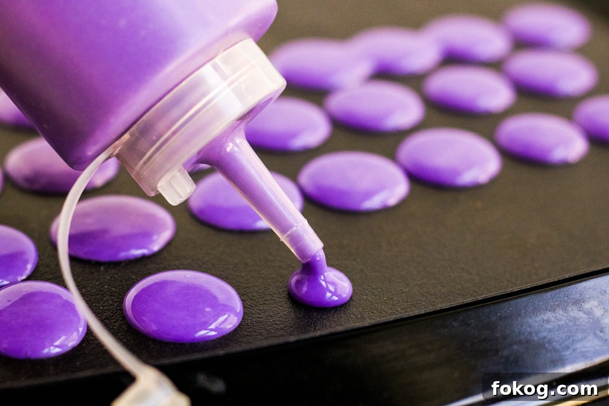Purple pancake batter being squeezed onto a griddle to make Halloween pancakes.