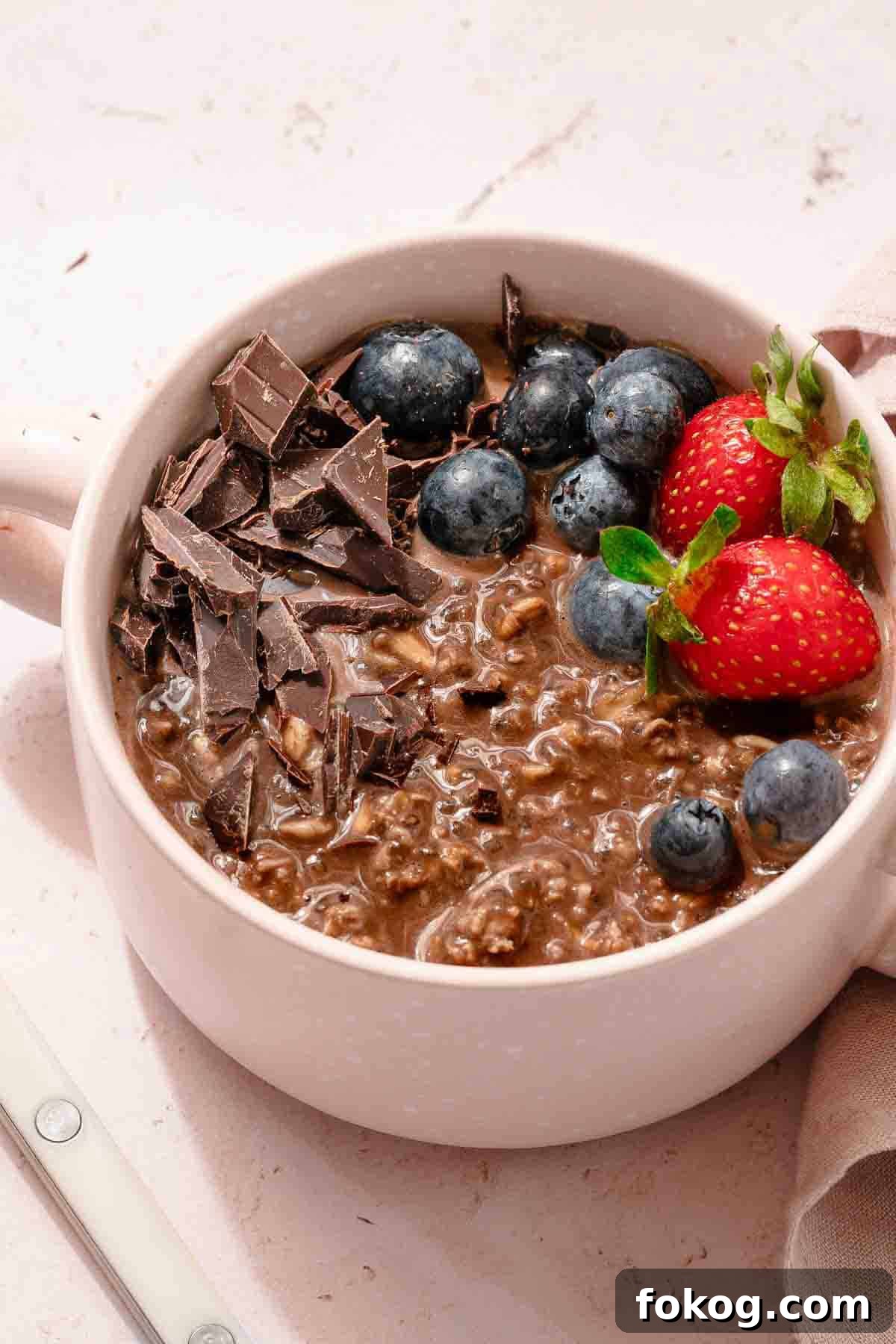 Creamy Chocolate Protein Overnight Oats 2 bowl of chocolate oatmeal with fruit garnish.