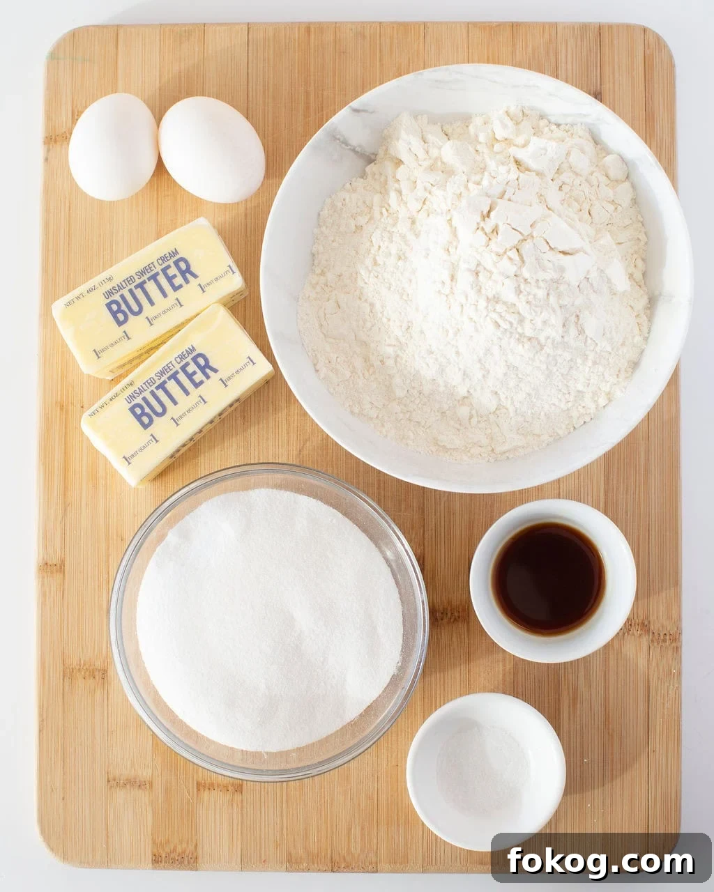 Ingredients to make sugar cookies on a wooden cutting board.