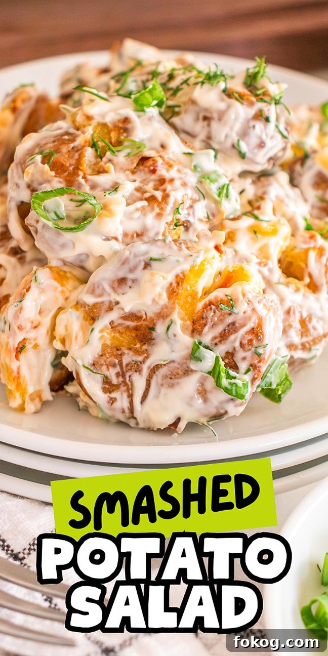 Close-up of a delectable smashed potato salad on a white plate, topped with creamy dressing and garnished with fresh herbs. 