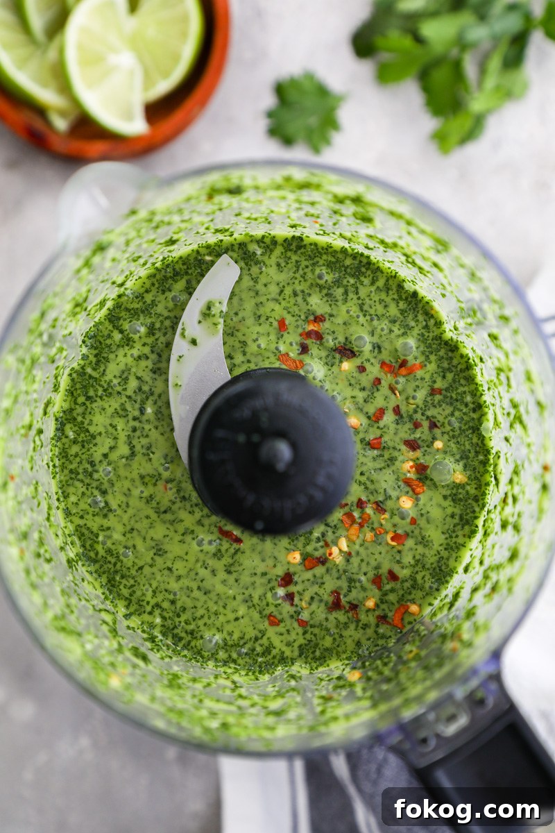 An overhead photo of a food processor filled with chimichurri sauce