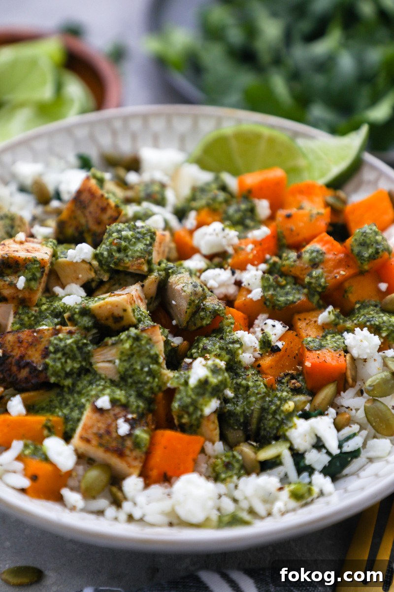 A close up photo of a chimichurri chicken and rice bowl drizzled with extra chimichurri sauce