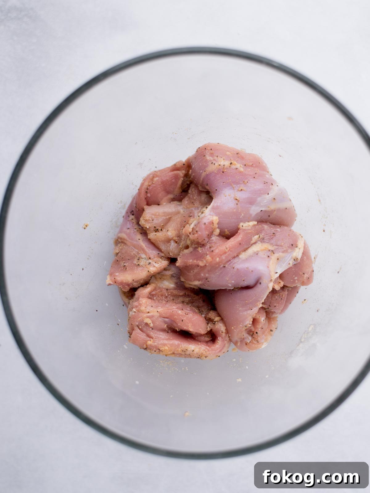 Crispy Buffalo Chicken Thighs Recipe for Dinner 4 boneless skinless chicken thighs seasoned in a mixing bowl
