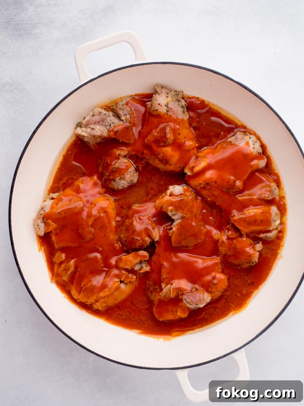 Crispy Buffalo Chicken Thighs Recipe for Dinner 6 chicken thighs seared in a skillet topped with buffalo sauce