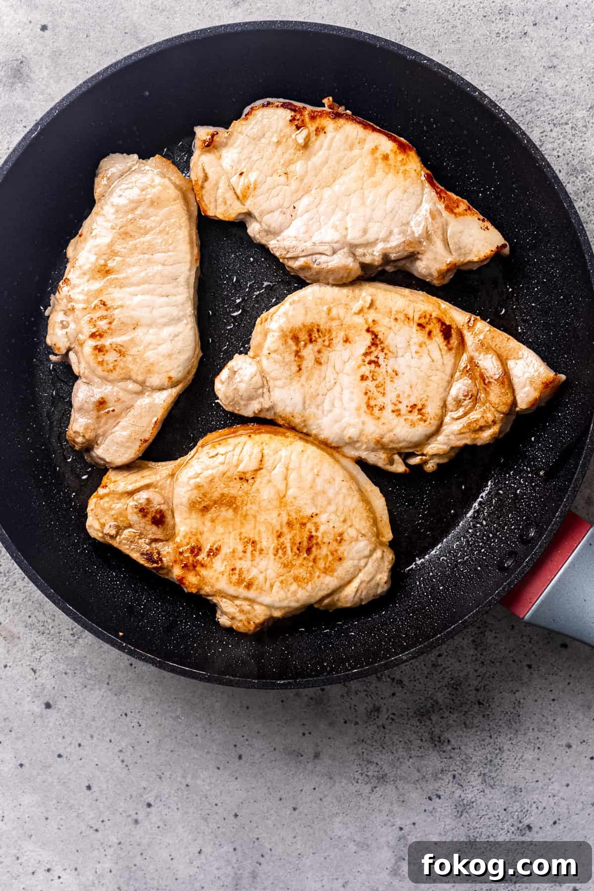 Searing pork chops in a pan.