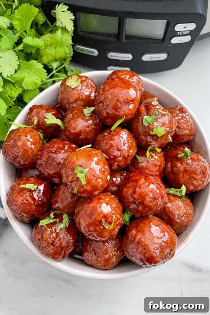 grape jelly meatballs in a serving bowl with cilantro on the side