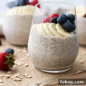 Creamy Vanilla Cinnamon Overnight Oats Recipe 10 Close up of a glass of overnight oats topped wit bananas, blueberries and strawberries next to raw oats and a spoon.