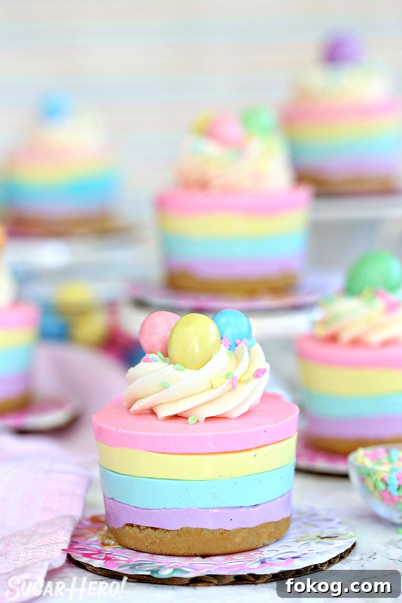 Easter no-bake mini cheesecakes topped with frosting, sprinkles, and candy eggs on colorful doilies.
