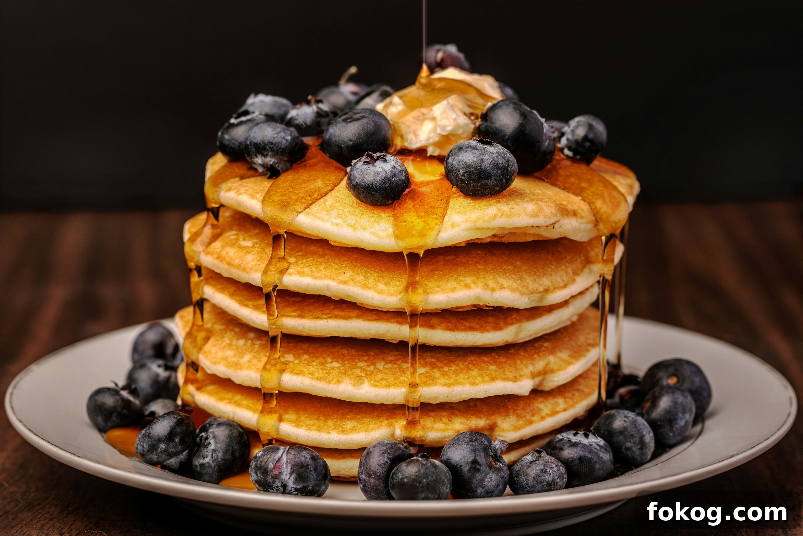 A stack of pancakes covered in blueberries and syrup