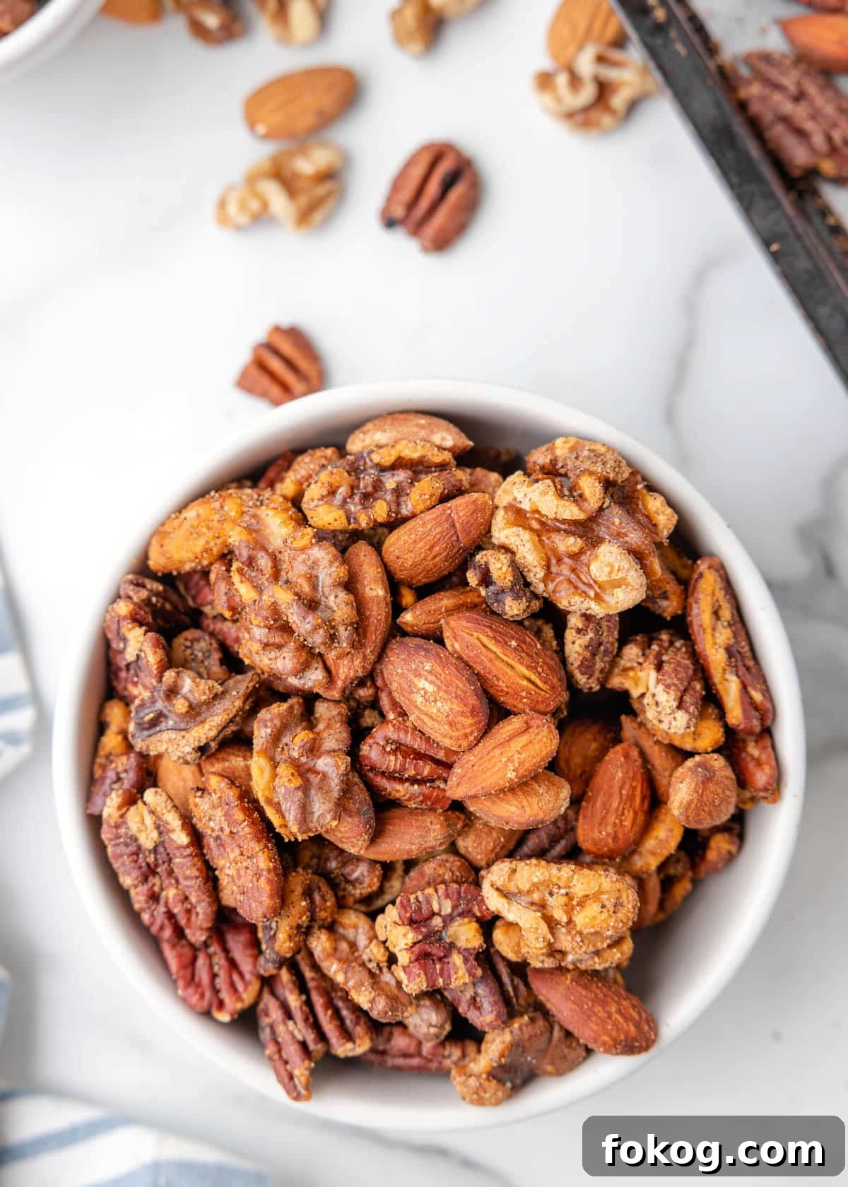 cajun spicy mixed nuts in a white bowl on a marble board