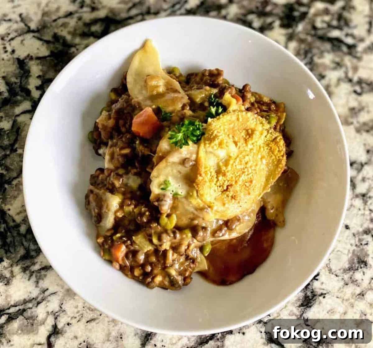 Hearty Vegan Shepherd's Pie Recipe for Comforting Weeknight Dinner 2 Cottage pie, also called vegan shepherd's pie recipe, is served in a bowl on the counter.