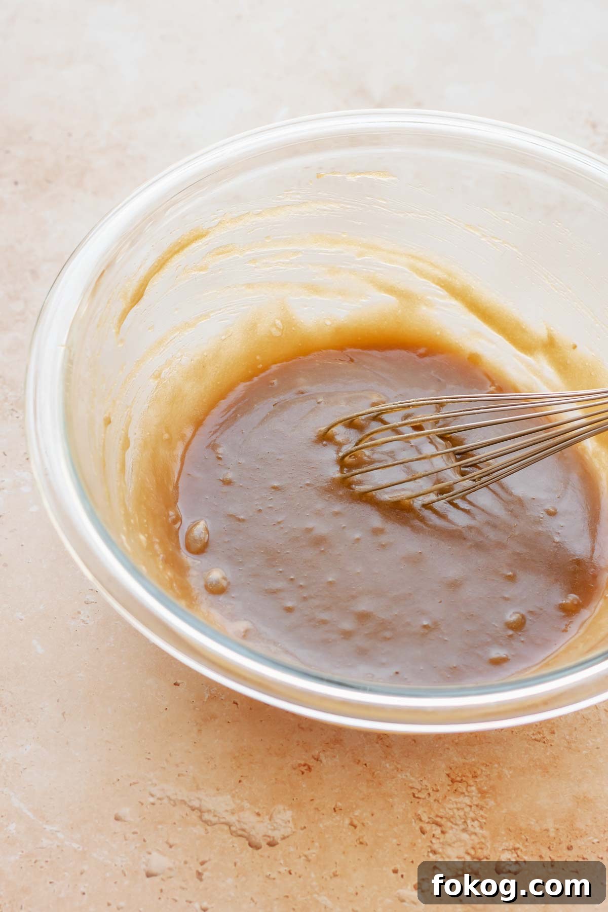 A whisk mixes sugar and butter in a bowl.