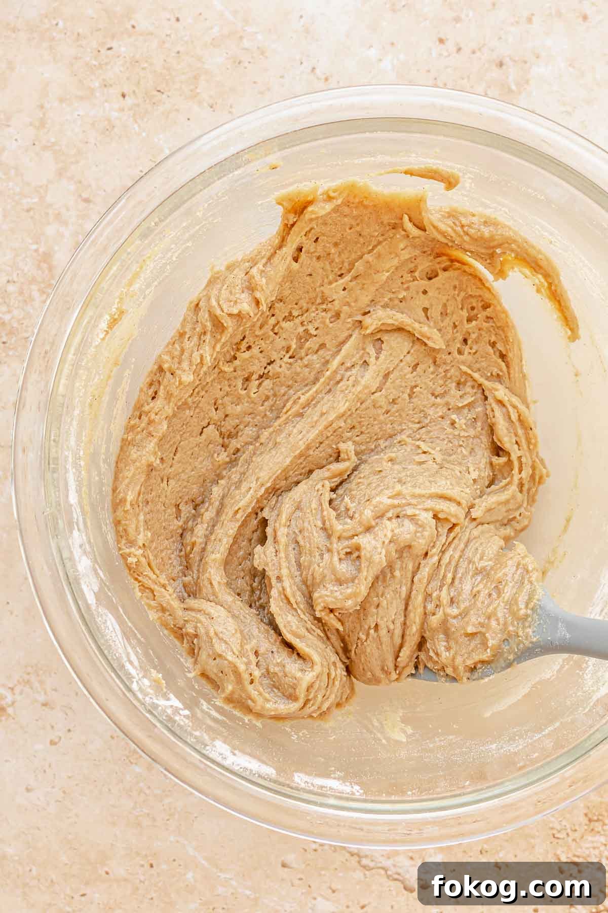 A spatula folds carrot cake batter in a bowl.