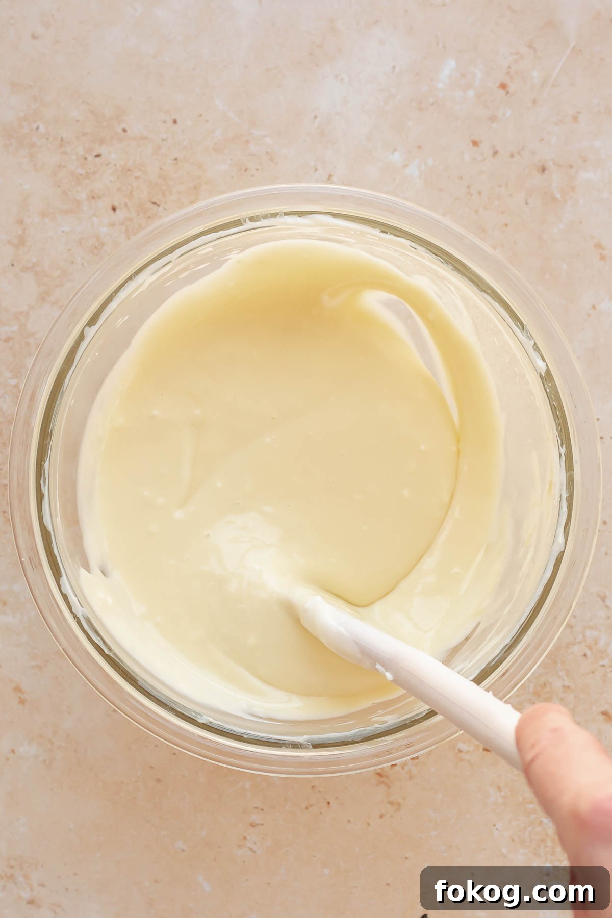 Finished cream cheese batter being stirred in a bowl.