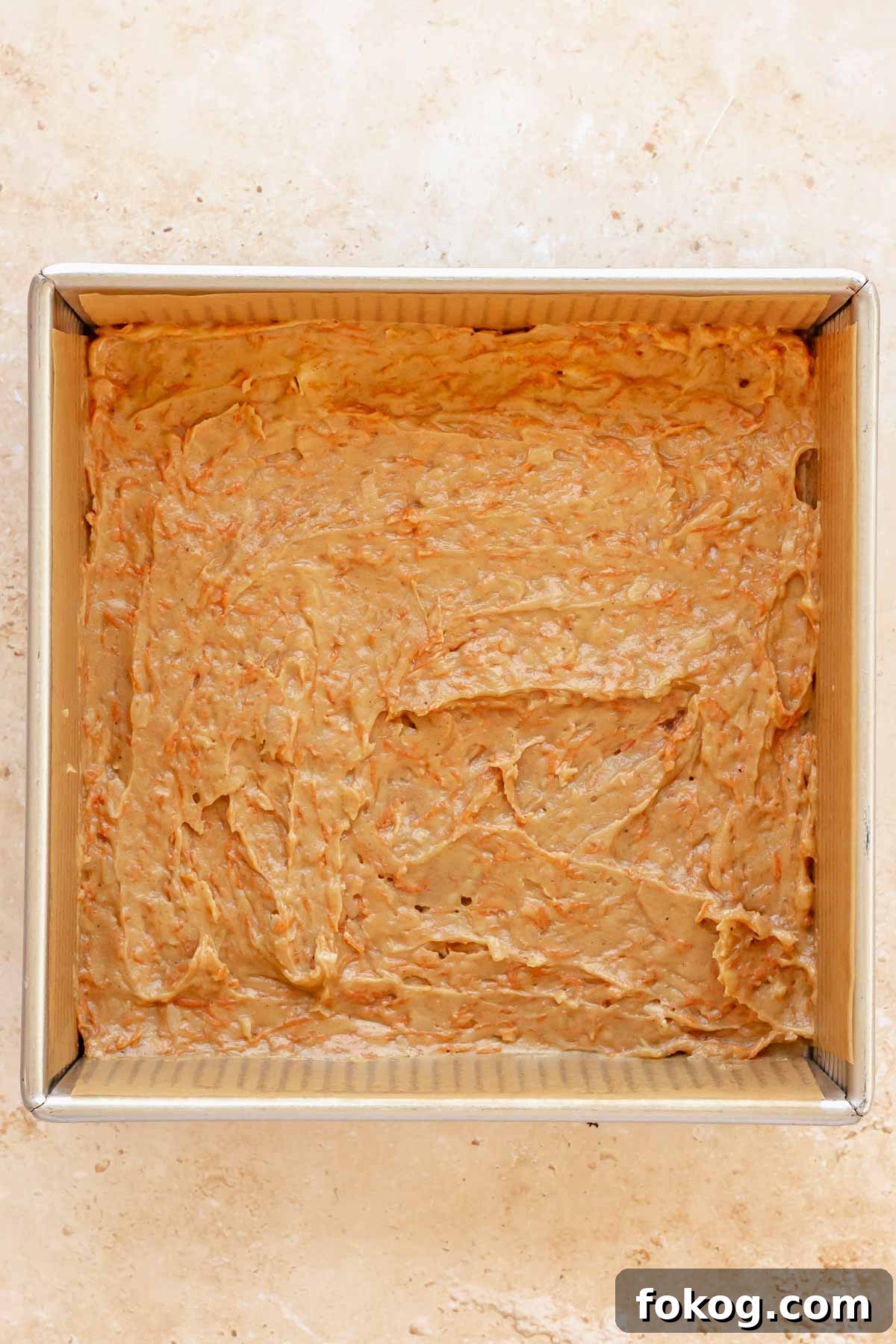 Carrot cake batter spread into a square pan.
