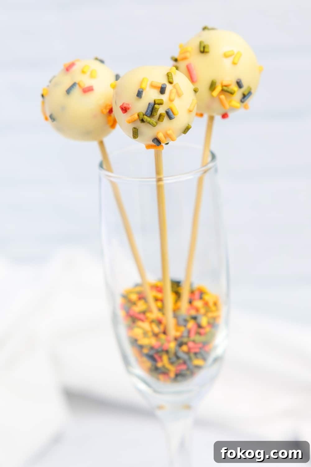 Keto Cottage Cheese Cake Pops Recipe — Low-Carb Dessert Bite 2 3 cake pops in a wine glass with sprinkles on the bottom