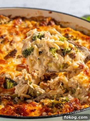 Chicken orzo pasta bake in a round, light green oven dish on a white background.
