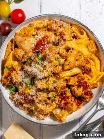 Creamy chicken and chorizo pasta in a white bowl on a white washed background.