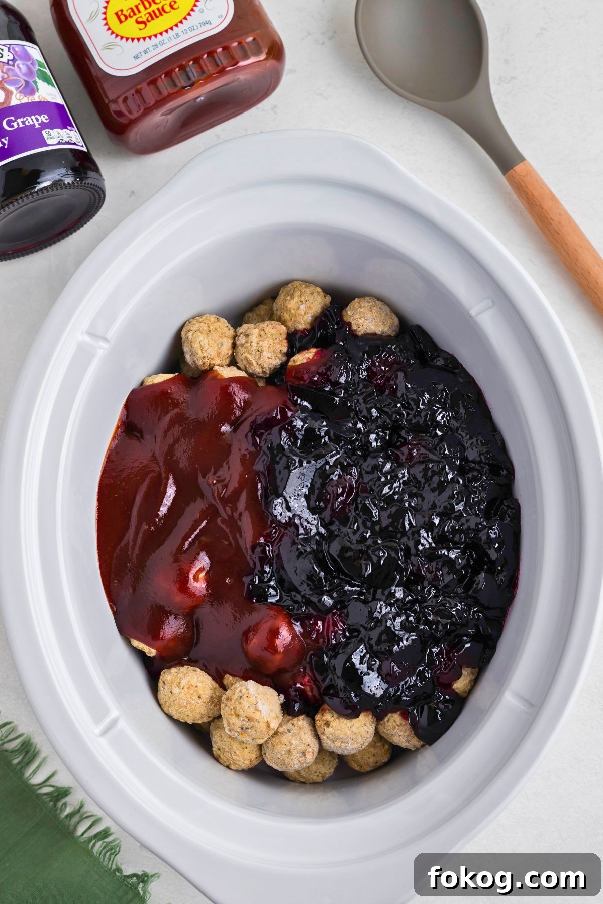 Sweet Grape Jelly Meatballs with Tangy Glaze Recipe 4 Frozen meatballs, grape jelly, and bbq sauce in a white slow cooker before cooking.