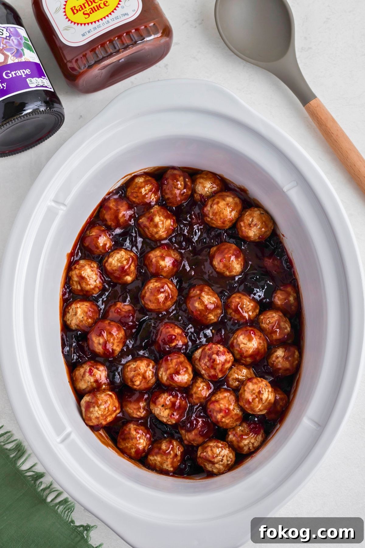 Sweet Grape Jelly Meatballs with Tangy Glaze Recipe 5 Grape jelly meatballs being cooked in a crock pot.