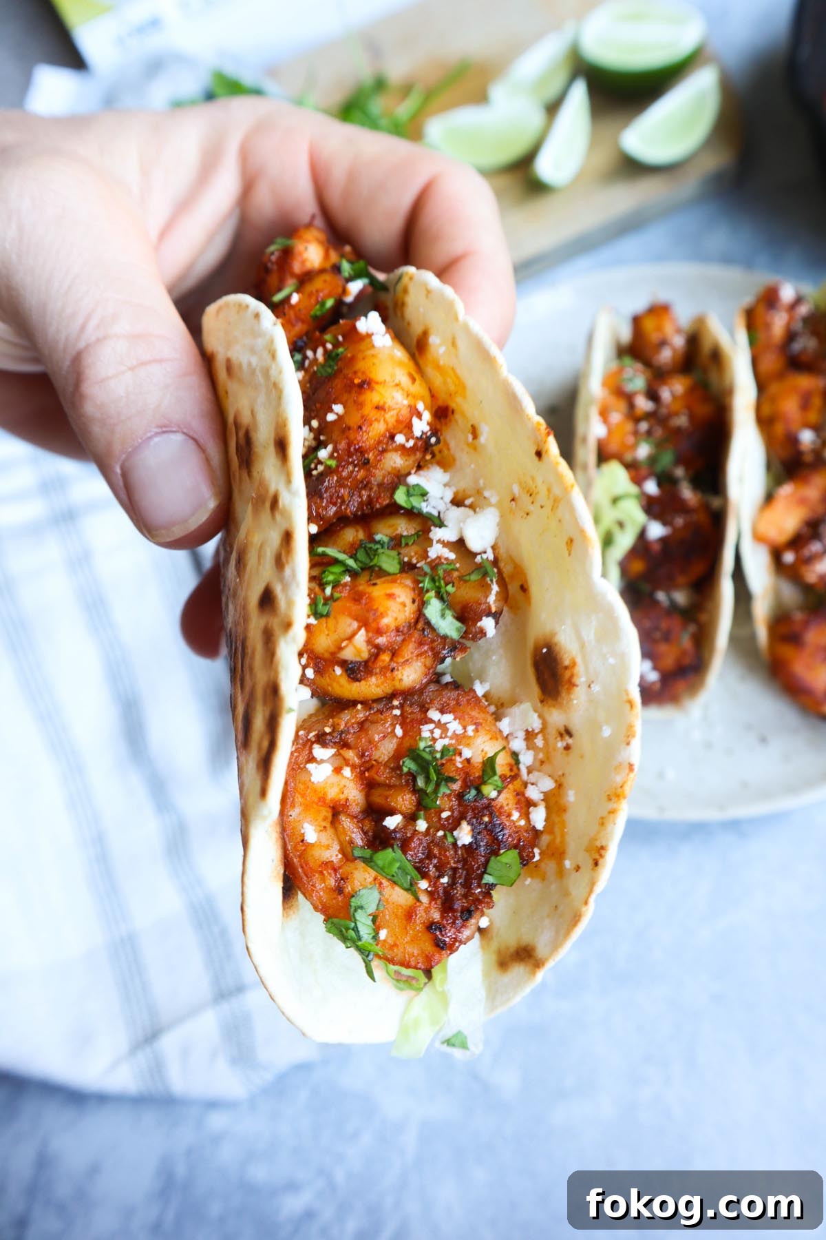 hand holding a taco de camaron with lettuce, cotija cheese, and cilantro