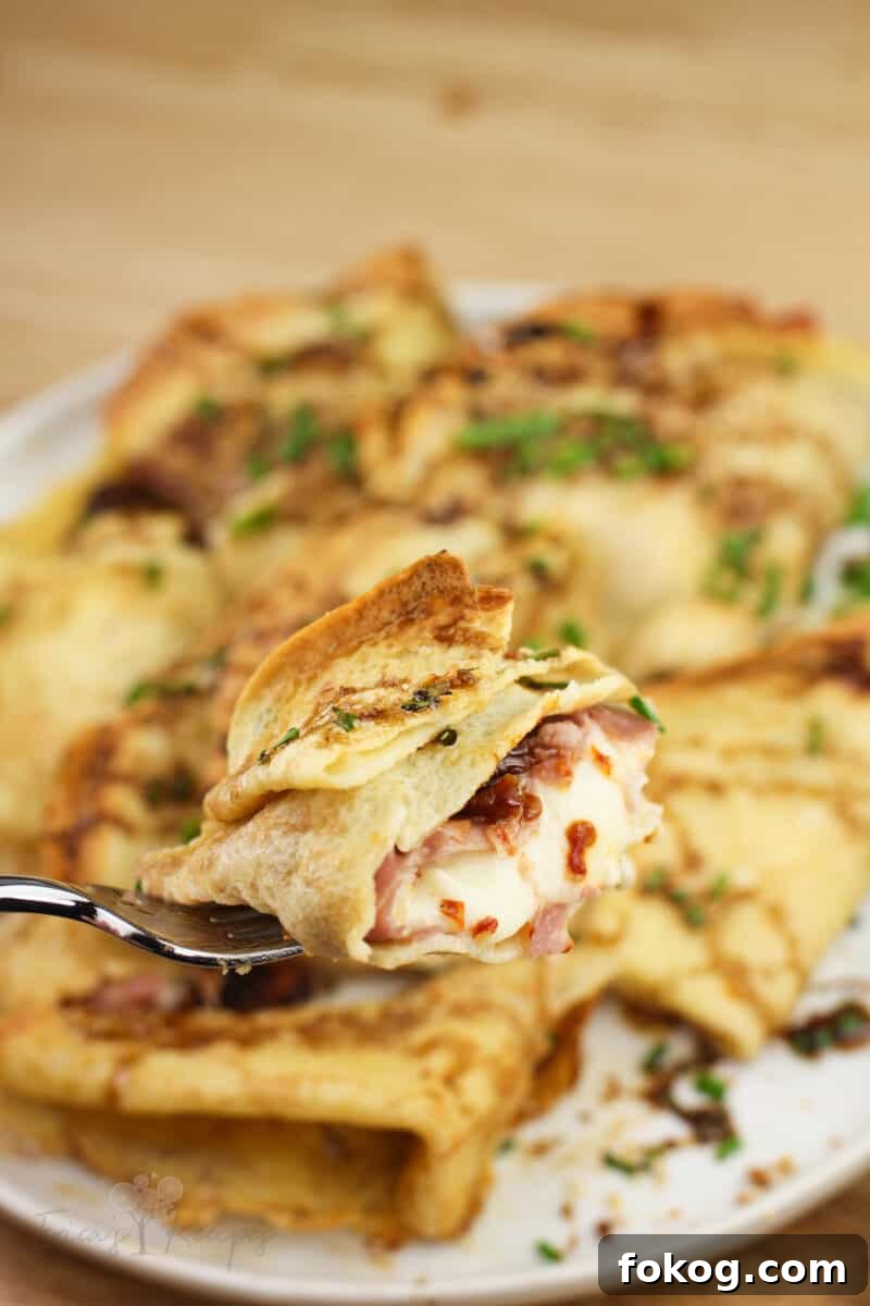 Smoked Salmon Crepes Recipe with Creamy Dill Filling 11 fork holding piece of crepe showing sun-dried tomato, prosciutto, and mozzarella filling