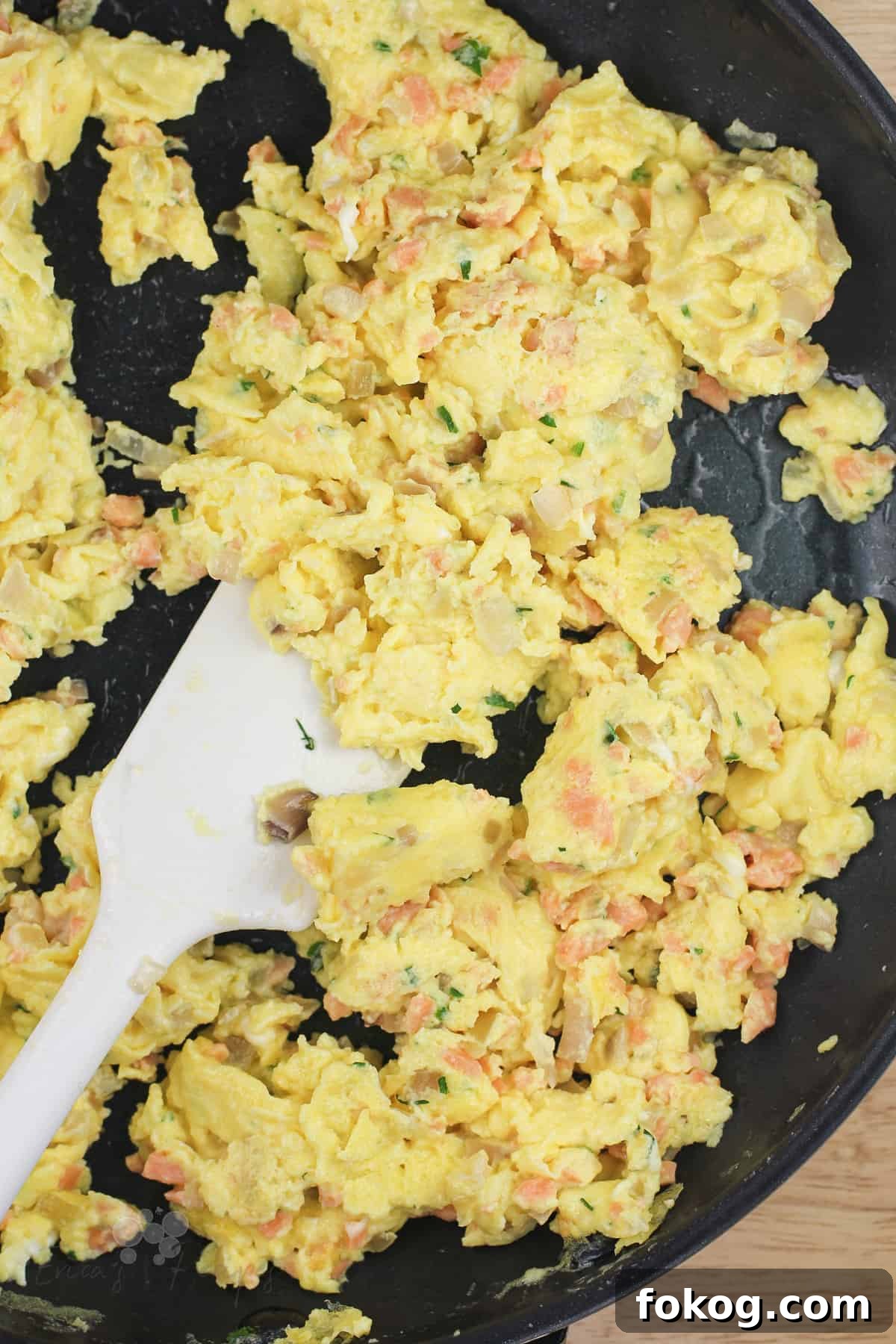 Smoked Salmon Crepes Recipe with Creamy Dill Filling 8 scrambled eggs with smoked salmon in skillet with white rubber spatula