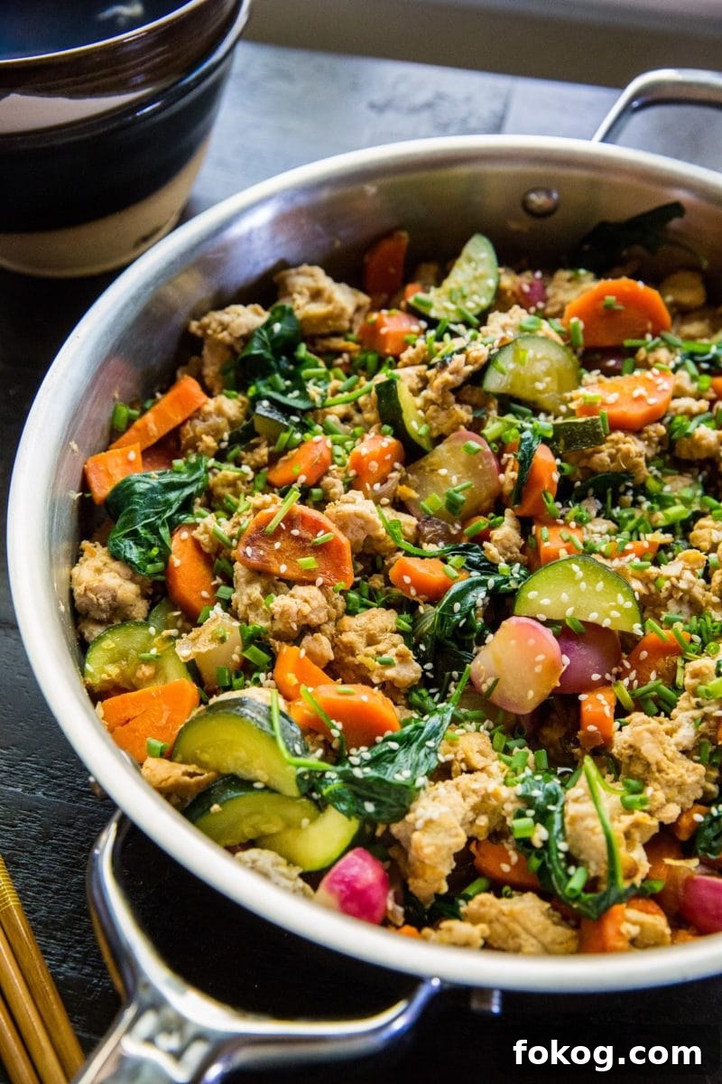 Stainless steel skillet at an angle, filled with ground turkey and vegetables.