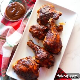Baked BBQ chicken, glazed with barbecue sauce, served on a white platter.