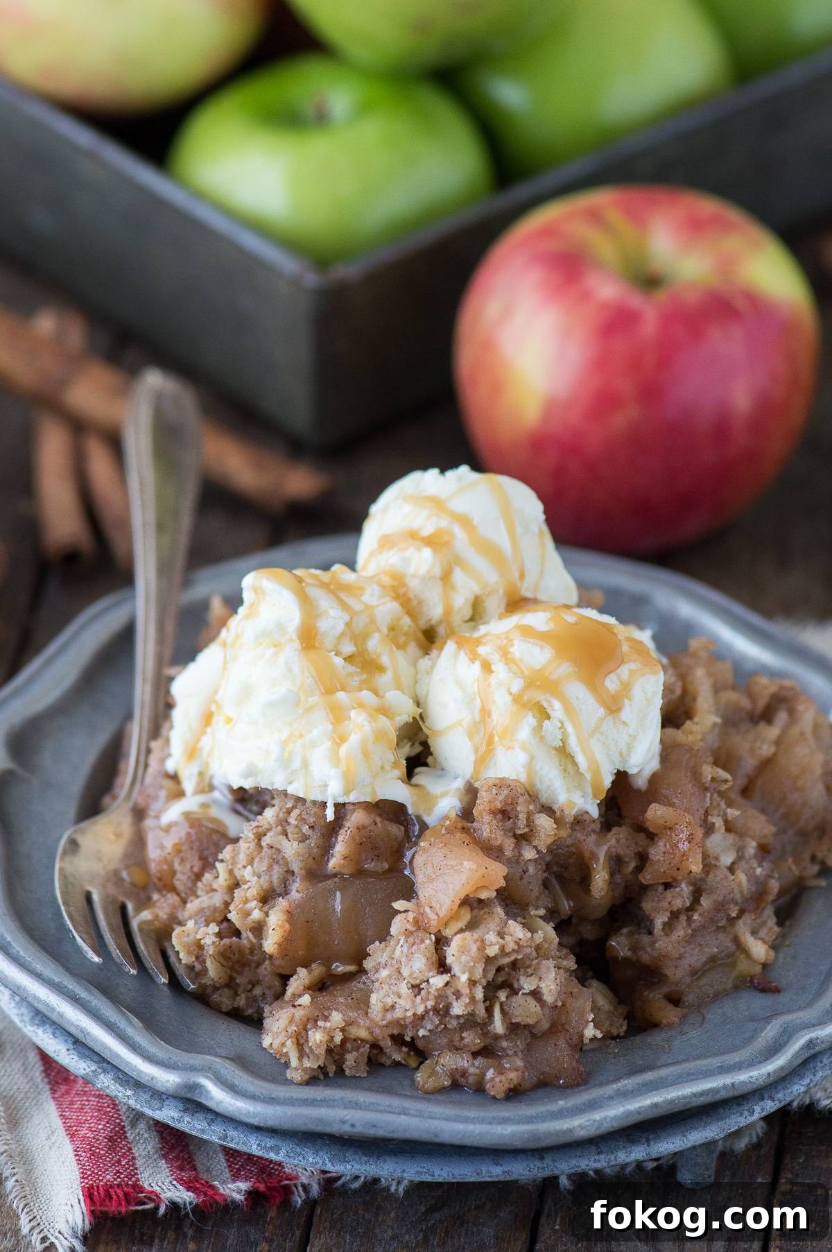 Slow-Cooker Apple Crisp with Cinnamon Oat Topping 2 scoop of crock pot apple crisp with 3 scoops of ice cream on metal plate