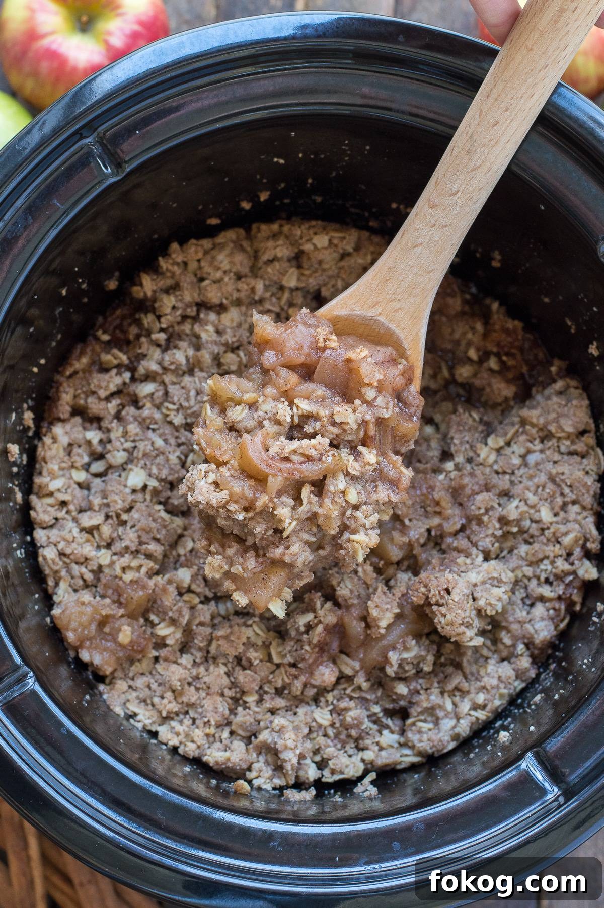 Slow-Cooker Apple Crisp with Cinnamon Oat Topping 3 crock pot apple crisp in black crock pot with wooden spoon