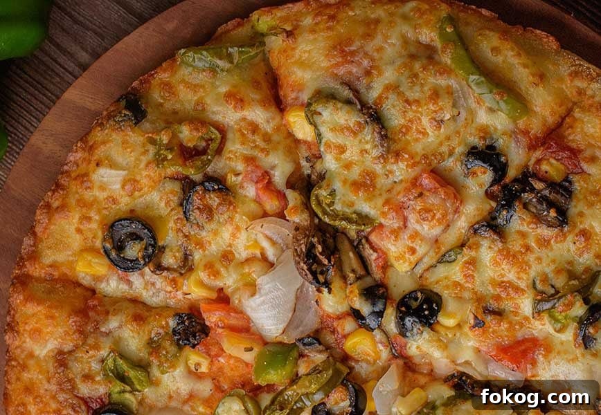 close up of keto mediterranean pizza, topped with olives, tomatoes and gooey cheese, low-carb and GF