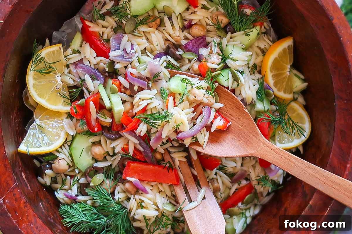 Orzo salad with fresh vegetables, served in a large wooden salad bowl