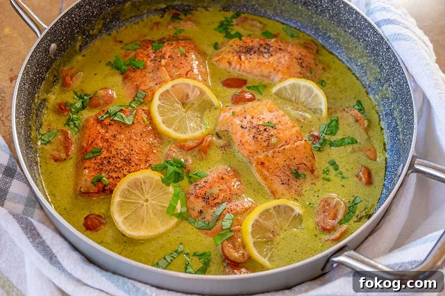 salmon in coconut pesto sauce topped with lemon slices and herbs, Italian recipe