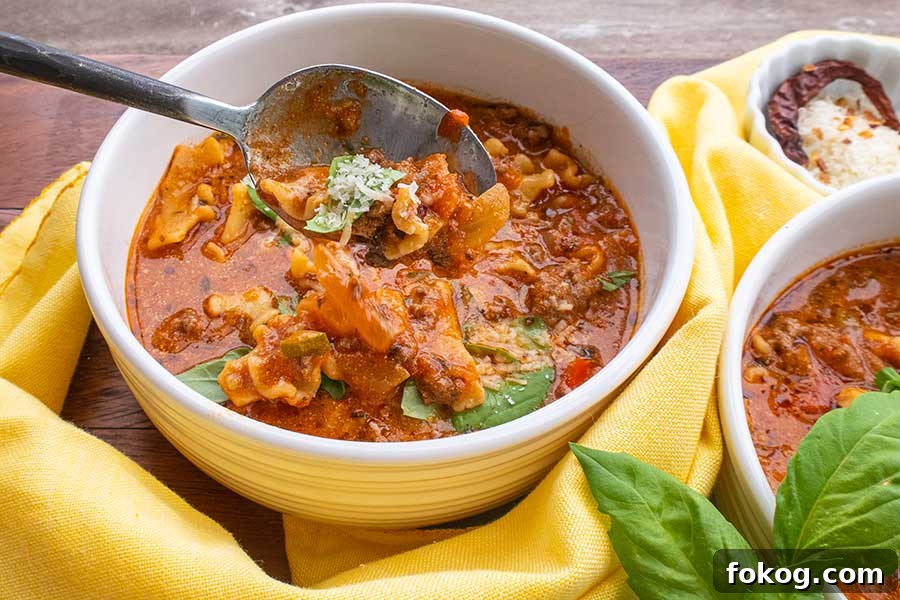  gluten free light tomato creamy lasagna soup with veggies in a bowl topped with cheese