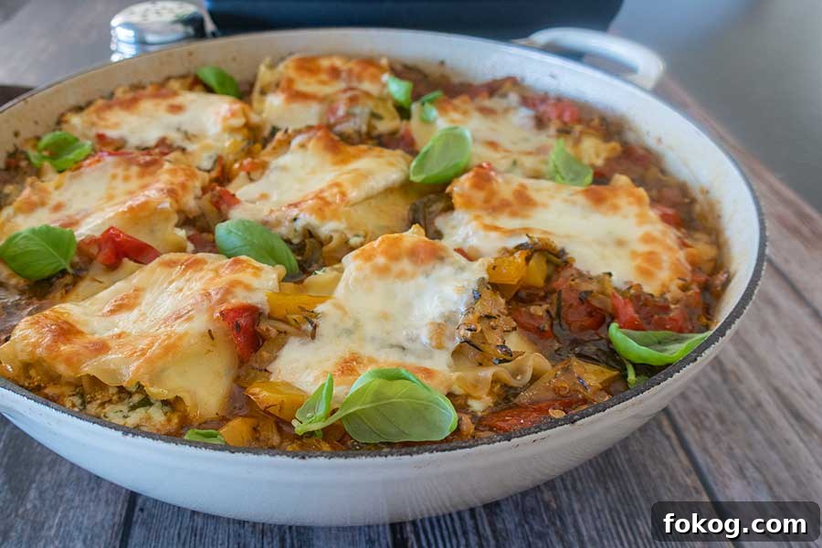 lasagna roll ups in a skillet topped with melted mozzarella and fresh basil