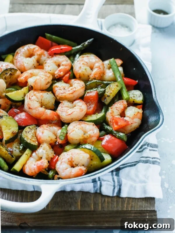 Garlic Butter Shrimp with Asparagus Recipe for Quick Weeknights 5 A white cast iron with shrimp and vegetables inside.