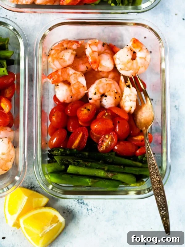 Garlic Butter Shrimp with Asparagus Recipe for Quick Weeknights 8 A glass meal prep container with shrimp, cherry tomatoes, and asparagus.