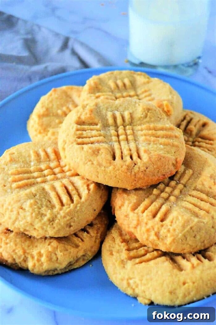 A plate of peanut butter cookies, made with cake mix and adorned with crisscross fork marks, sits next to a glass of milk.