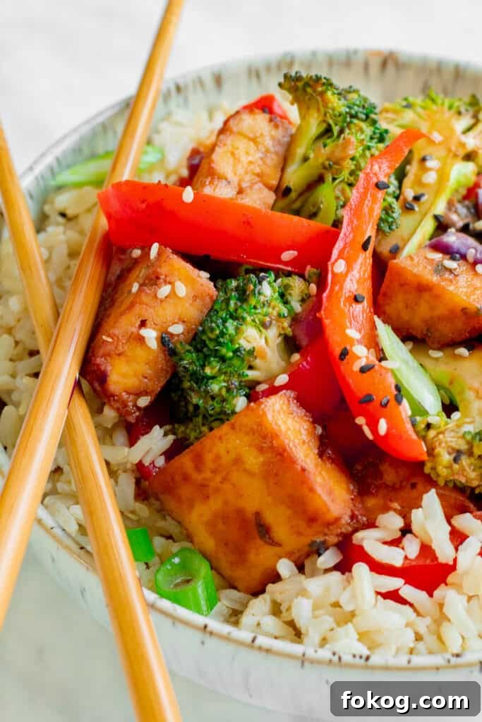 Close up of Crispy Tofu Hoisin Stir-fry in bowl with chopsticks. Vegan, GF & Healthy! Georgie Eats.