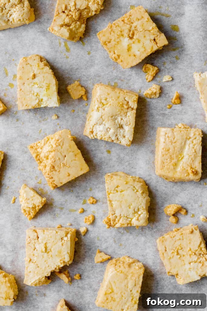 Chunks of uncooked tofu on baking tray.