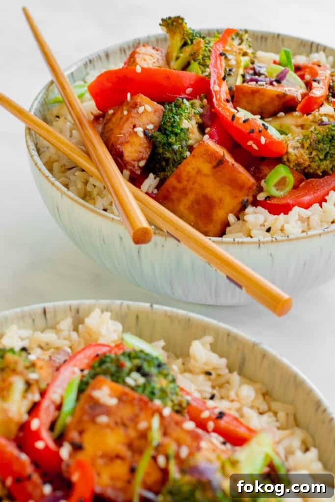 Two bowls of Crispy Tofu Hoisin Stir-fry in with chopsticks. Vegan, GF & Healthy! Georgie Eats.