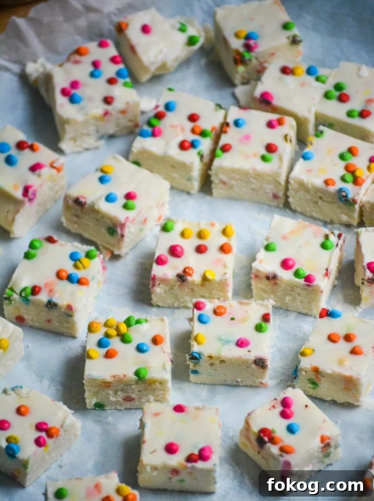 squares of rainbow chip frosting fudge spread out on a piece of crinkled parchment paper