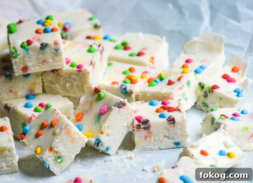 a pile of chunks of rainbow chip frosting, two ingredient fudge shown on a crinkled piece of white parchment paper