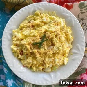 Creamy Low-Carb Keto Egg Salad Recipe for Quick Meals 10 Keto egg salad in bowl next to spoon and lettuce leaves.