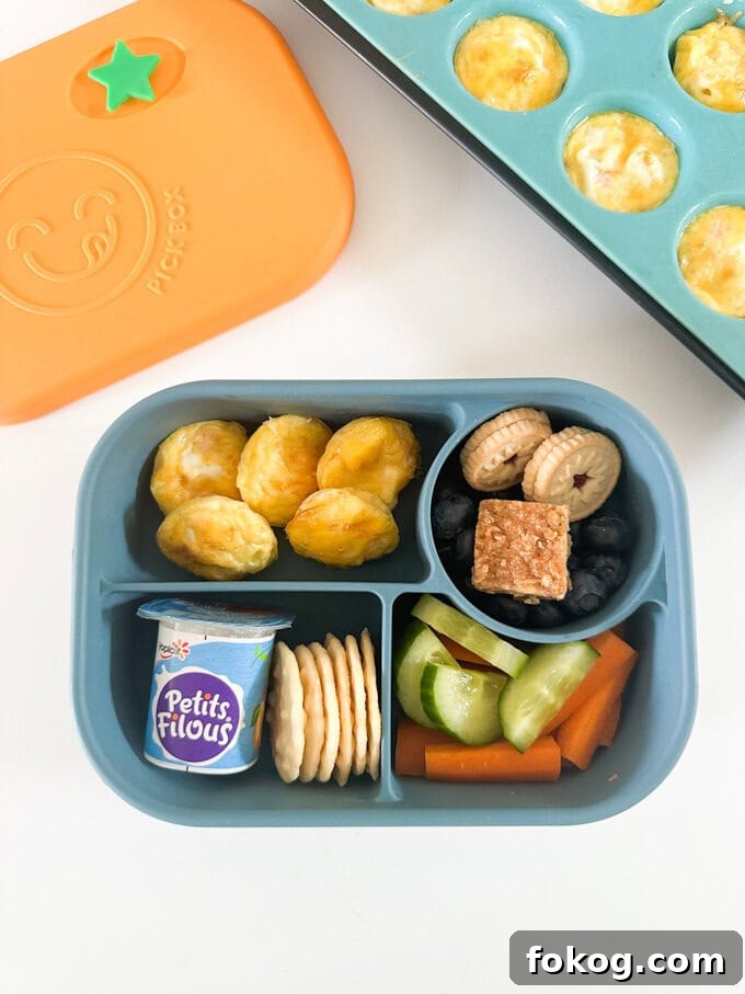 Five mini egg bites served in a child's blue lunchbox.