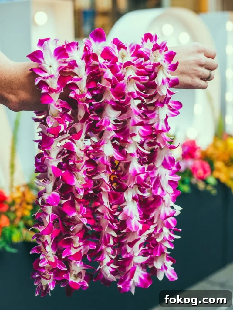 Arm holding out 5 purple fresh orchid lei.