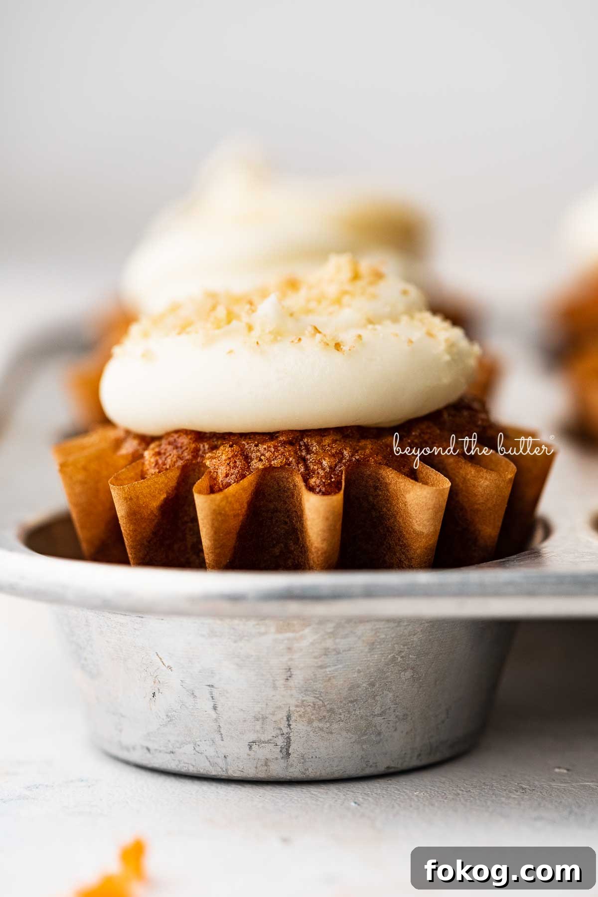 Closeup image of carrot cake cupcakes in a vintage cupcake tin | © Beyond the Butter®