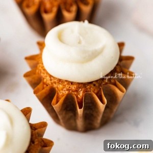 Super moist carrot cake cupcakes topped with cream cheese frosting on a white background.